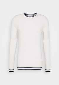Bílý svetr s dlouhým rukávem a žebrovanou strukturou. Má kulatý výstřih a námořnicky modré pruhované detaily na límci a rukávech.