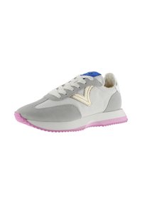 Witte en grijze sneaker met paarse zool, vetersluiting aan de voorkant, blauwe tonglabel en beige V-vormig logo aan de zijkant.