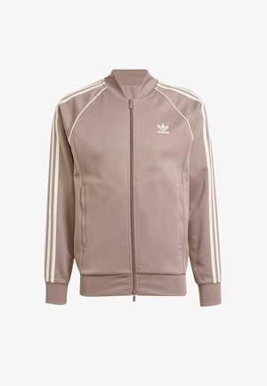 Jasnobrązowa kurtka zapinana na zamek, wykonana z gładkiego materiału, z białymi paskami akcentującymi wzdłuż ramion i rękawów oraz małym logo na klatce piersiowej.