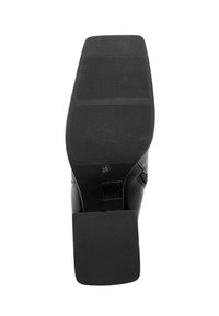 Czarna skórzana podeszwa buta z kwadratowym obcasem, poziomymi liniami gripu i rozmiarem 36 oznaczonym w pobliżu łuku.