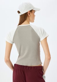 Kortærmet skjorte i grå ribbet stof med hvide detaljer, der har en tætsiddende pasform og rund halsudskæring, parret med maroon shorts.
