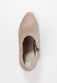 Botín de ante beige hasta el tobillo con puntera puntiaguda y cremallera lateral. Forro interior floral y textura suave. Diseño de tacón plano y sutil.