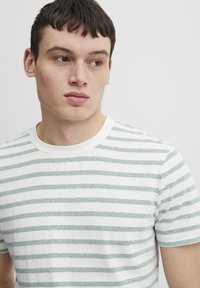 Stribet kortærmet t-shirt i hvid og lys grøn. Har en rund halsudskæring og en blød tekstur med vandrette striber.
