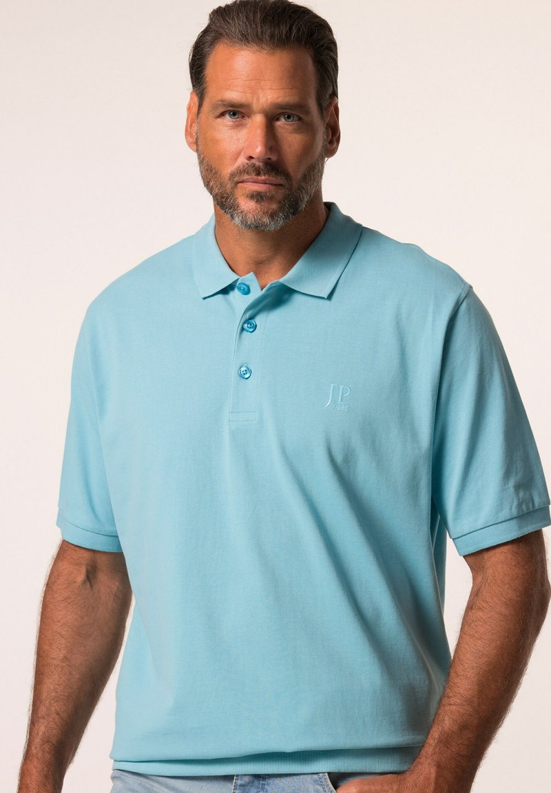 Ljusblå kortärmad polo t-shirt i mjukt tyg, med en klassisk krage, tre knappar och en prägling av logotypen på bröstet.