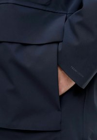 Jūrinis vandeniui atsparus švarkas su elegantišku dizainu, matoma kišenė ir etiketė "TECHFUSION" ant rankovės. Lygi, lanksti audinio tekstūra.