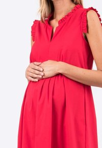 Abito rosso senza maniche con scollo arricciato, vestibilità morbida, arricciature in vita e tessuto liscio, progettato per l'abbigliamento prenatale.