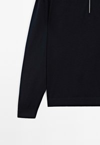 Black long-sleeve top made of soft fabric, featuring a high collar and a zip closure down the front, with ribbed cuffs and hem.