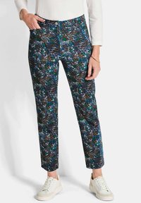 Pantaloni con un motivo astratto colorato in toni di blu, verde e marrone; vestibilità slim; tasche frontali; abbinati a sneakers bianche.