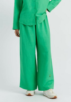 Groene linnen broek met wijde pijpen en een textuurafwerking, gecombineerd met een bijpassend overhemd met knopen, met subtiele borduursels op de broek.