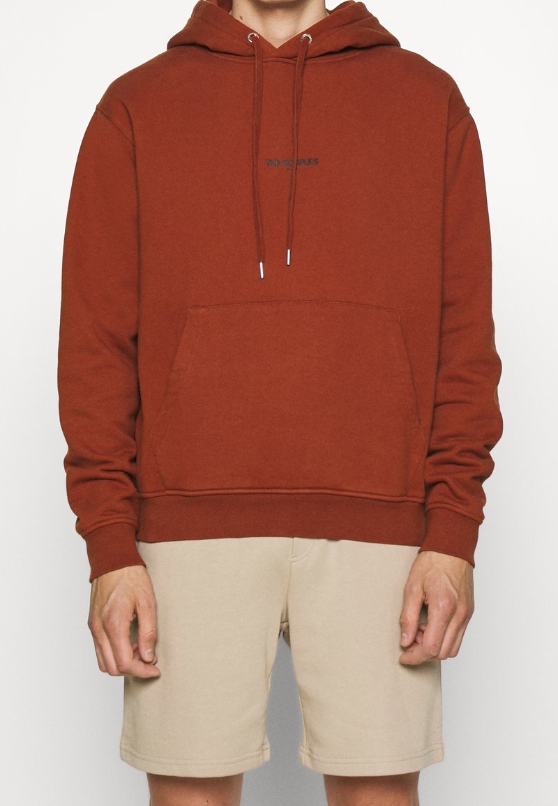 Rostfärgad huvtröja med en känguruficka, justerbara dragsnören och diskret frontlogotyp i svart. Bomullsblandning, avslappnad passform.