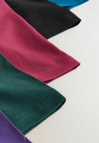 Spalvingi audiniai su rankovėmis, žalia, bordo, juoda, teal ir violetinė spalvomis, sudėlioti sluoksniais šviesiame fone.