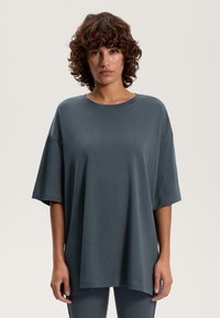 Överdimensionerad kolgrå T-shirt, tillverkad av mjuk bomullstyg, med korta ärmar, rundad halsringning och avslappnad passform.