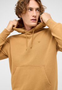 Brązowa bluza z kapturem ze ściągaczem, przednią kieszenią i subtelnym logo. Miękki materiał o fakturowanej powierzchni, z ściągaczami na mankietach.