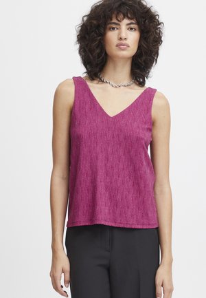 Fuchsia ærmeløs top med V-hals, struktureret stof, løs pasform og lige kant, parret med sorte bukser mod en neutral baggrund.