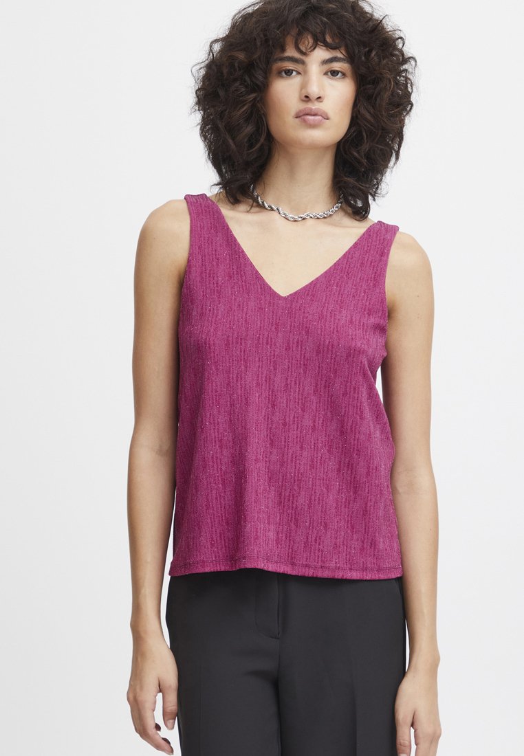 Fuchsia ærmeløs top med V-hals, struktureret stof, løs pasform og lige kant, parret med sorte bukser mod en neutral baggrund.