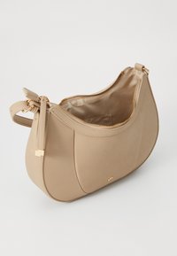 Sac à épaule en cuir beige avec fermeture éclair dorée partiellement ouverte, bandoulière réglable avec quincaillerie dorée, et petit logo doré à l'avant.