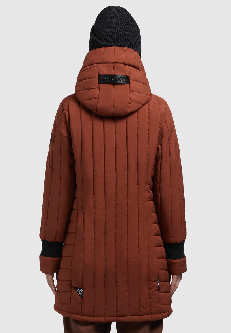Gepolsterte orange-braune Jacke mit Kapuze, vertikal gestepptem Design, schwarzen Bündchen und Logodetail am Hals, strukturierte Oberfläche.