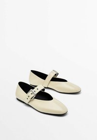 Creme læder balletflade sko med spidse tæer, der har en bred rem og sølv spænde detaljer. Sort indre, flad sål.