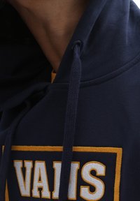Sudadera con capucha de color navy con acentos en amarillo. Presenta un gran logo "VANS", cordones y una tela texturizada para mayor comodidad.