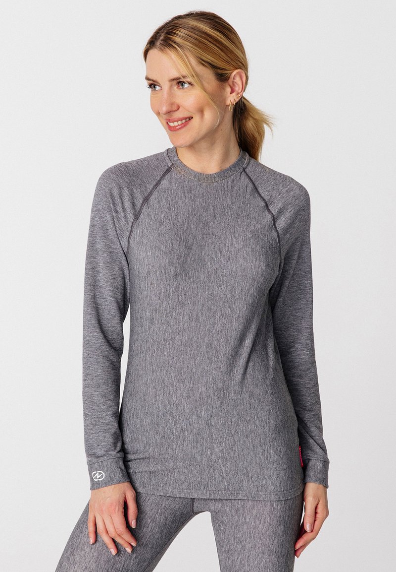 Camiseta deportiva gris de manga larga con una textura suave, mangas raglán y un cuello redondo. Presenta un logo en el puño izquierdo.