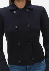 Marineblauwe gebreide cardigan met een double-breasted ontwerp, voorzien van zes ronde zwarte knopen en een verspreide kraag. Gestructureerde stof.