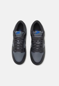 Nike superge v črni in sivi mrežasti in usnjeni kombinaciji, z grobo površino in vezalnim oblikovanjem. Modra znamka na jeziku.