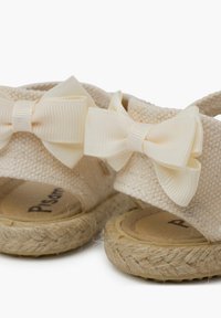 Lichtbeige espadrille sandalen van geweven stof, met twee crèmekleurige lintstrikken. Natuurlijke jute zool met een gestructureerde afwerking.