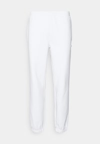 Bílé tepláky z měkké látky, s elastickým páskem a manžetami. Obsahují boční kapsy a mají minimalistický design.