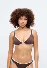 Brown bikini set featuring a textured, ribbed material. The top has white accents, a keyhole detail, and gold-tone hardware.