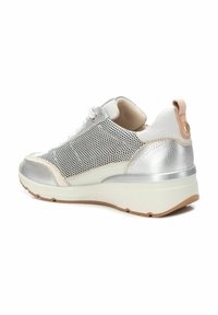 Zapatillas de malla plateadas con un upper de cuero texturizado blanco y plateado, una suela de goma ligera y un interior suave beige. Presentan un bucle en la parte trasera.