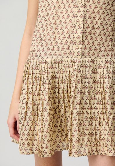 Vestido de tela beige con estampado floral, con cierre de botones y falda plisada. Presenta pequeñas flores en tonos rojo oscuro y azul.