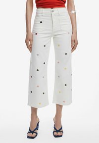 Weiße, verkürzte Jeans mit mehrfarbiger Blumenstickerei. Verfügt über fünf Taschen, einen Knopfverschluss und einen geraden, lockeren Schnitt.