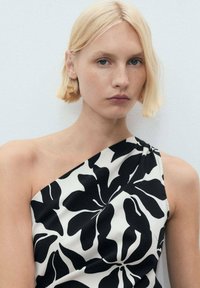 Rochie cu un umăr, având un model floral alb-negru pe o țesătură netedă, care îmbrățișează silueta cu falduri moi și un design minimalistic.