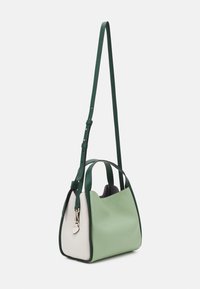 Strukturalna torebka z zielonej i białej skóry z teksturą. Posiada odpinany zielony pasek oraz srebrne ozdoby. Okrągły kształt.