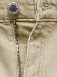 Pantaloni din denim bej, cu un buton metalic argintiu, fermoar vizibil și detalii de cusătură ordonată pe margini și buzunare.