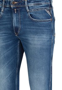 Blauwe spijkerbroek met een licht afgeplate textuur, vijfzakkenontwerp en contrasterende stiksels langs de naden.