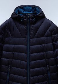 Veste matelassée bleu marine avec capuche, fermeture éclair intégrale à l'avant et poches latérales zippées, conçue pour le temps froid.