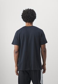Schwarzes Baumwoll-T-Shirt mit kurzen Ärmeln, Rundhals und lockerer Passform, das eine glatte Textur und ein minimalistisches Design aufweist.