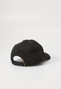 Casquette noire en tissu texturé, dotée d'un pic incurvé, d'une sangle ajustable à l'arrière et d'une couleur noire uniforme.