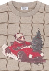 Felpa grigia a girocollo con motivo a griglia marrone, caratterizzata da un orso in una macchina rossa che tiene un abete natalizio. Texture morbida, design giocoso.