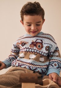 Neulepaita, jossa sininen pohja ja ruskeat traktori-, lammas- ja eläinaiheet; resorireunukset hihoissa ja pyöreä pääntie; teksturoitu kangas.