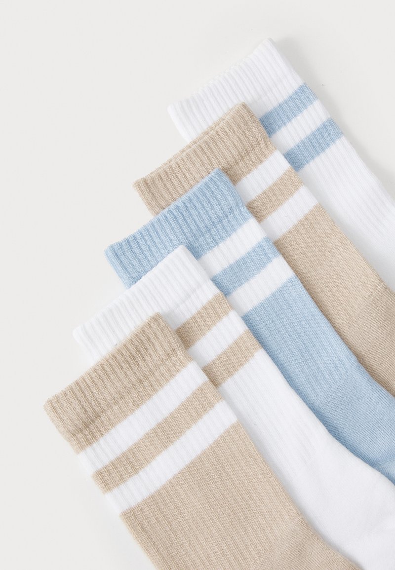 Set von vier Socken mit geripptem Design. Die Farben umfassen Beige, Hellblau, Weiß und gestreifte Muster in Beige und Blau.