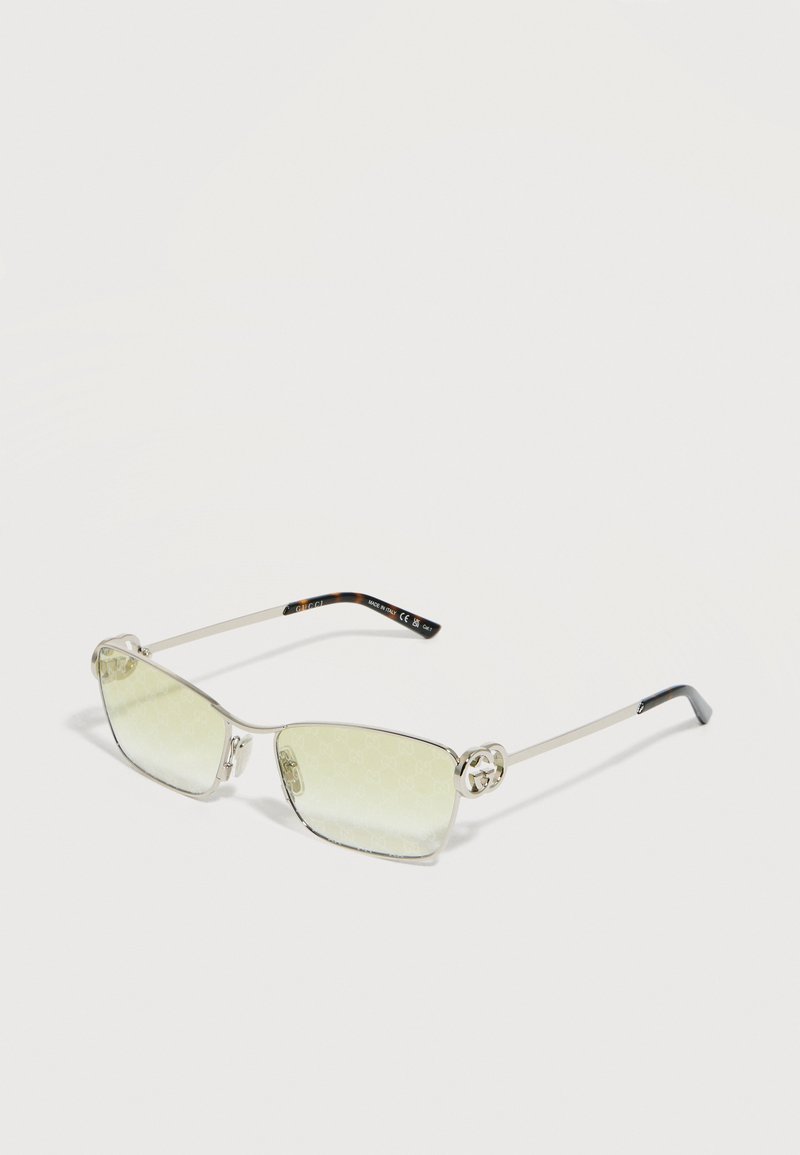 Λεπτά ορθογώνια γυαλιά ηλίου με ασημί πλαίσιο και ανοιχτοκίτρινους φακούς, με το λογότυπο της Gucci στις πλευρές, σε λευκό φόντο.