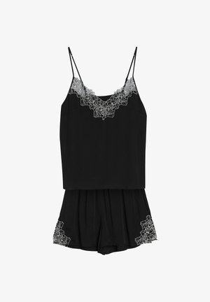 Czarny komplet na ramiączkach i szorty wykonane z gładkiego materiału, z białą koronką w kwiaty zdobiącą linię dekoltu i dół.