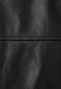 Μαύρο δερμάτινο υλικό με λεία υφή και διακριτική γυαλάδα, με μια εμφανή ραφή που διασχίζει οριζόντια την επιφάνεια.