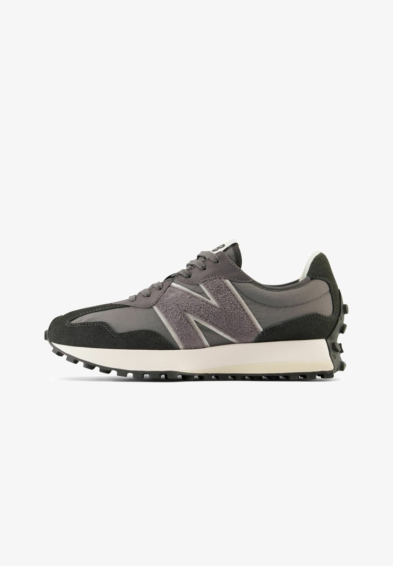 Baskets de sport grises et noires avec logo « N » texturé, laçage à l'avant, semelle intermédiaire blanche et semelle extérieure noire cloutée, vues de profil.