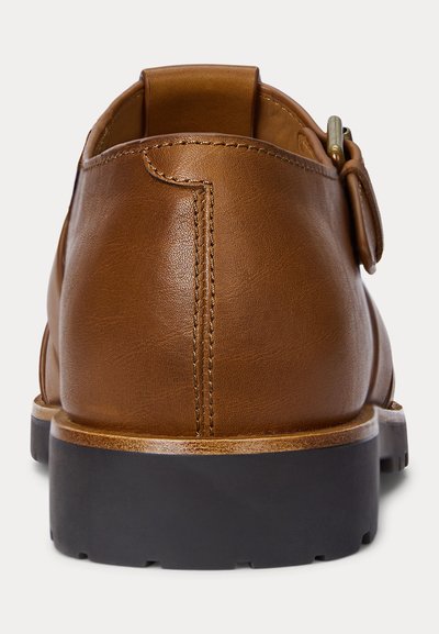 Rjava usnjena obleka z vezenim šivom na zadnji strani, zaponko na strani in debelim črnim gumijastim podplatom.