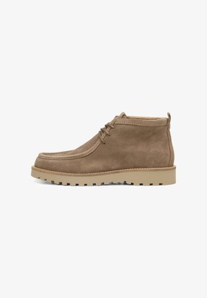 Botas de tornozeleira em suede castanho com ponta arredondada, design com atacadores e sola de borracha texturizada para melhor aderência. Salto reforçado com uma alça.