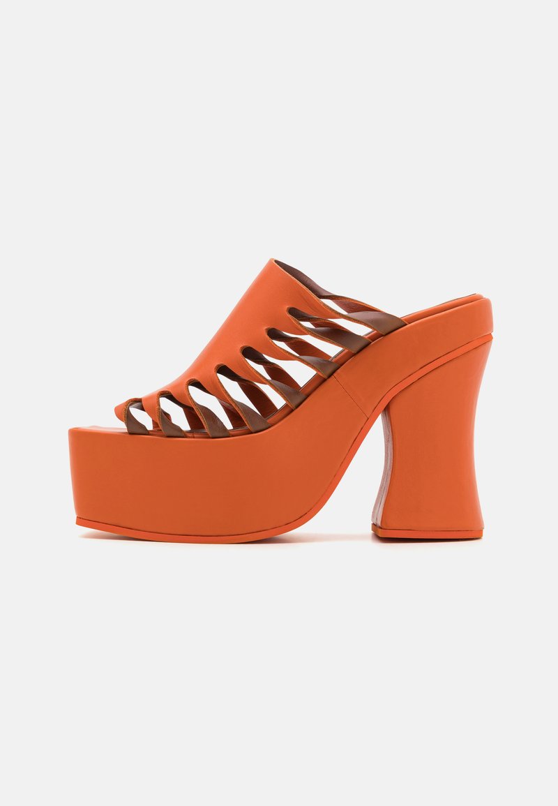 Oranje platform mules met een dikke, gebogen bruine hak. Bevat uitsneden over de tenen en een gladde rubberachtige afwerking.