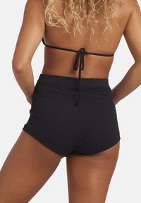 Costumi da bagno neri in tessuto testurizzato, con vita alta e design aderente, dotati di una cintura liscia e senza hardware visibile.